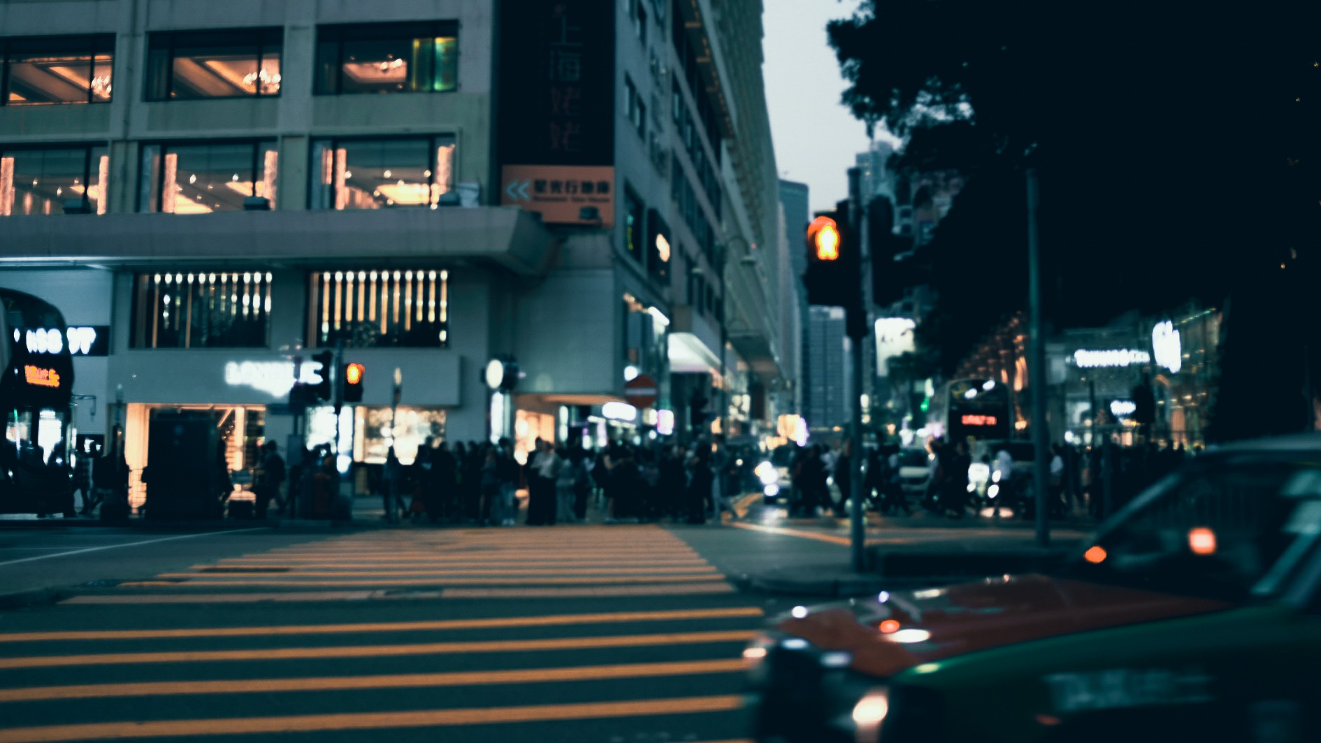 Pedestrian crosswalk at a Shanghai intersection during twilight, with blurred taxi lights and glowing storefronts.