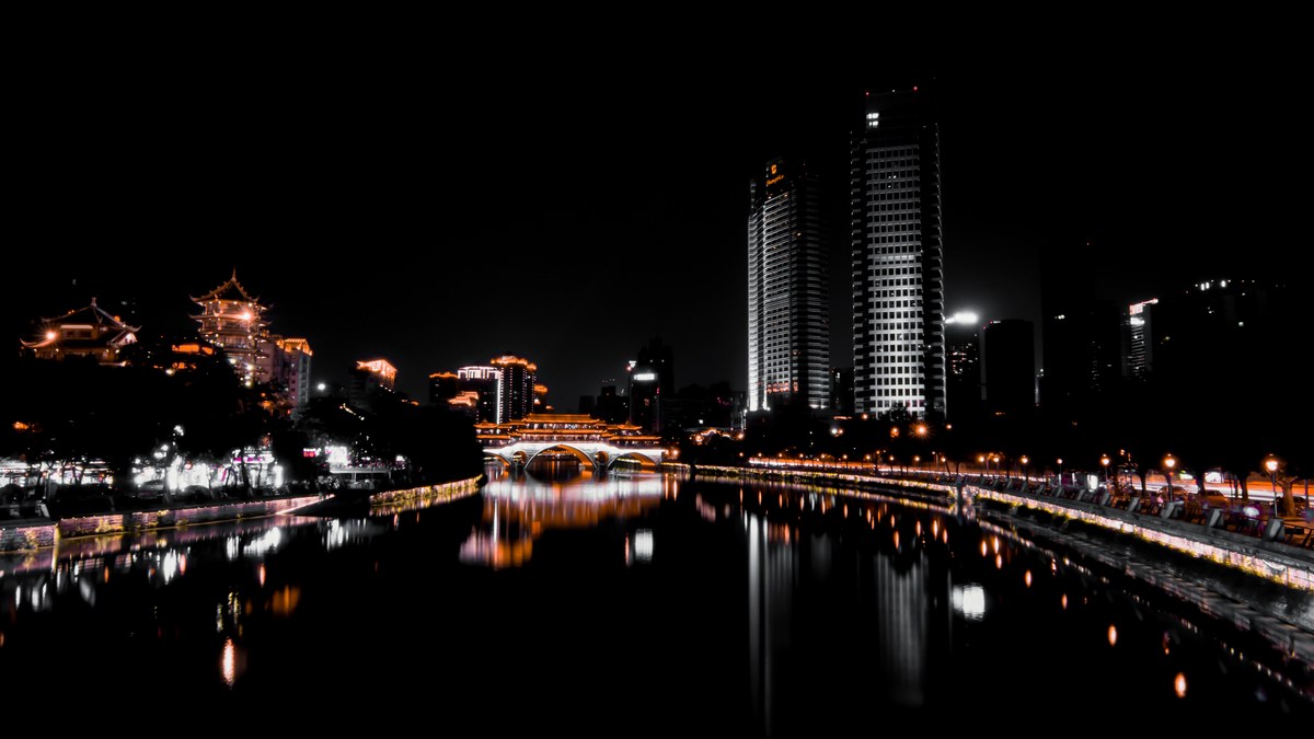 Chengdu night landscape showing traditional pavilions and modern towers reflecting on the tranquil Jin River.
